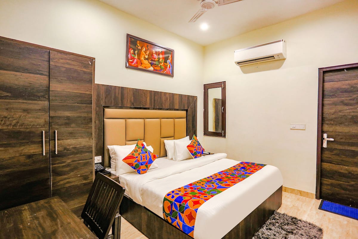 A hotel room with a bed, a wardrobe, a desk, and an air conditioning unit.