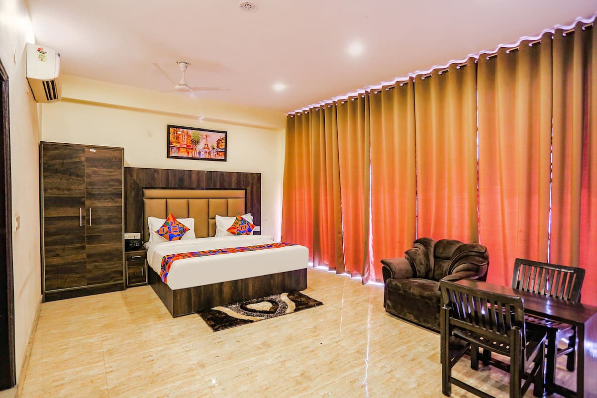 A hotel room with a bed, a desk, a chair, a wardrobe, and curtains.