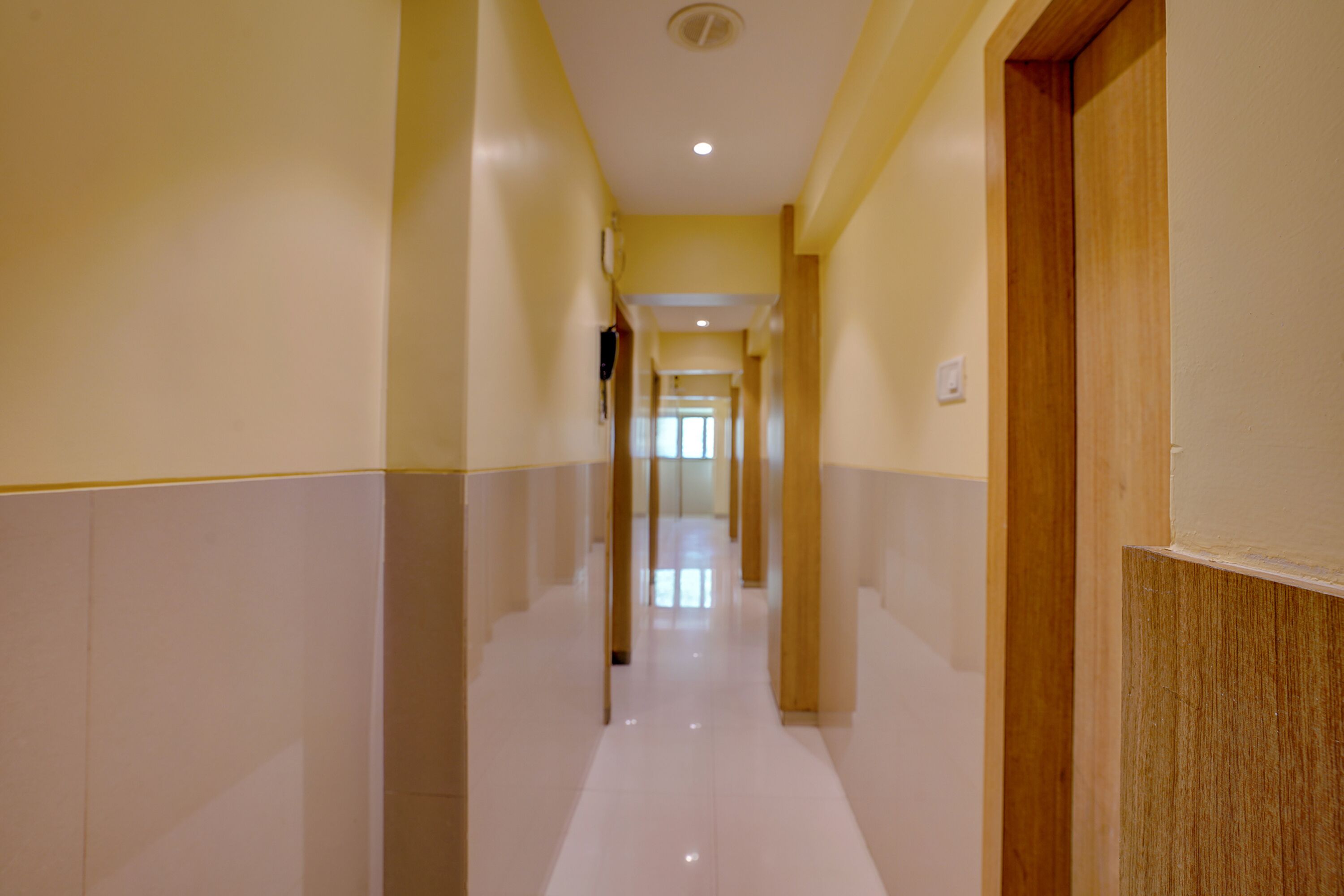 A long, narrow hallway with a tiled floor and yellow walls.