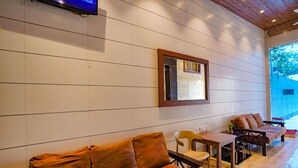 A modern interior with a sofa, a table, and chairs, a TV mounted on the wall, and a window with a view.