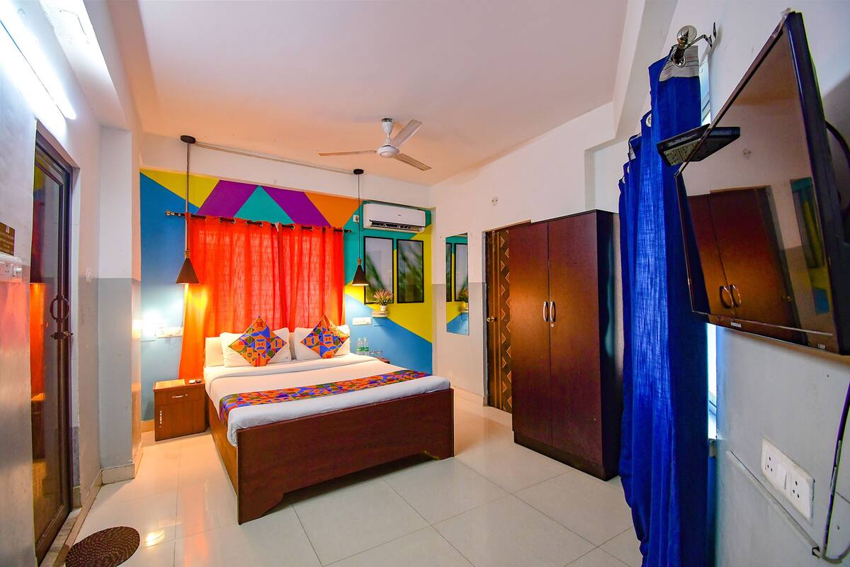 A bedroom with a bed, a ceiling fan, a TV, and a wardrobe.