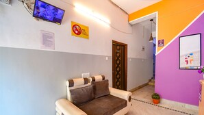 A room with a sofa, a television, a no smoking sign, and a door. - Fabhotel Luxury Stay (Bidhannagar)