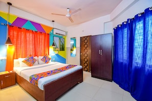 A bedroom with a bed, curtains, a wardrobe, and a ceiling fan. - Fabhotel Luxury Stay (Bidhannagar)