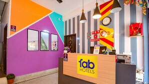 A hotel reception area with a colorful wall, a reception desk, and a clock. - Fabhotel Luxury Stay (Bidhannagar)