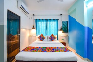 A hotel room with a bed, curtains, two wall-mounted lamps, a nightstand, and a TV on the wall. - Fabhotel Luxury Stay (Bidhannagar)