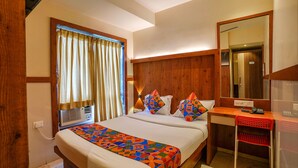 A hotel room with a large bed, a desk with a chair, a mirror, and a window with curtains. - Fabexpress Super 7 Inn (Navi Mumbai)