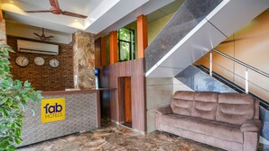 A lobby with a reception desk, a staircase, and a sofa. - Fabexpress Super 7 Inn (Navi Mumbai)