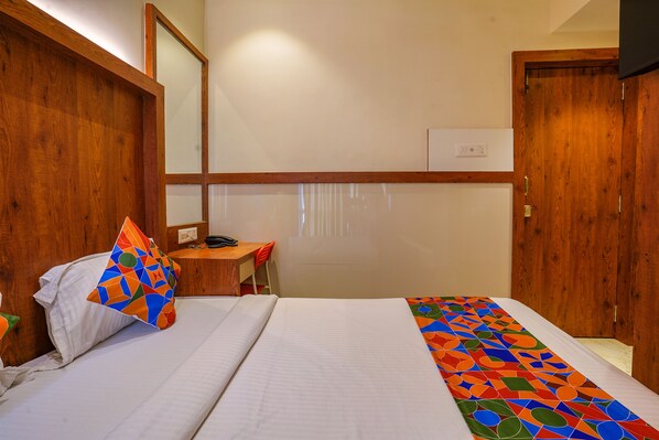 A hotel room with a bed, a desk, and a mirror.