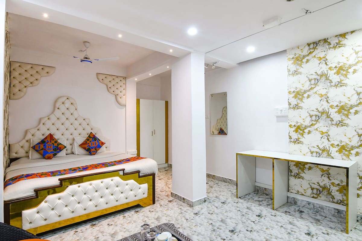 A bedroom with a tufted headboard, a bedside table, a mirror, and a marble-patterned floor.