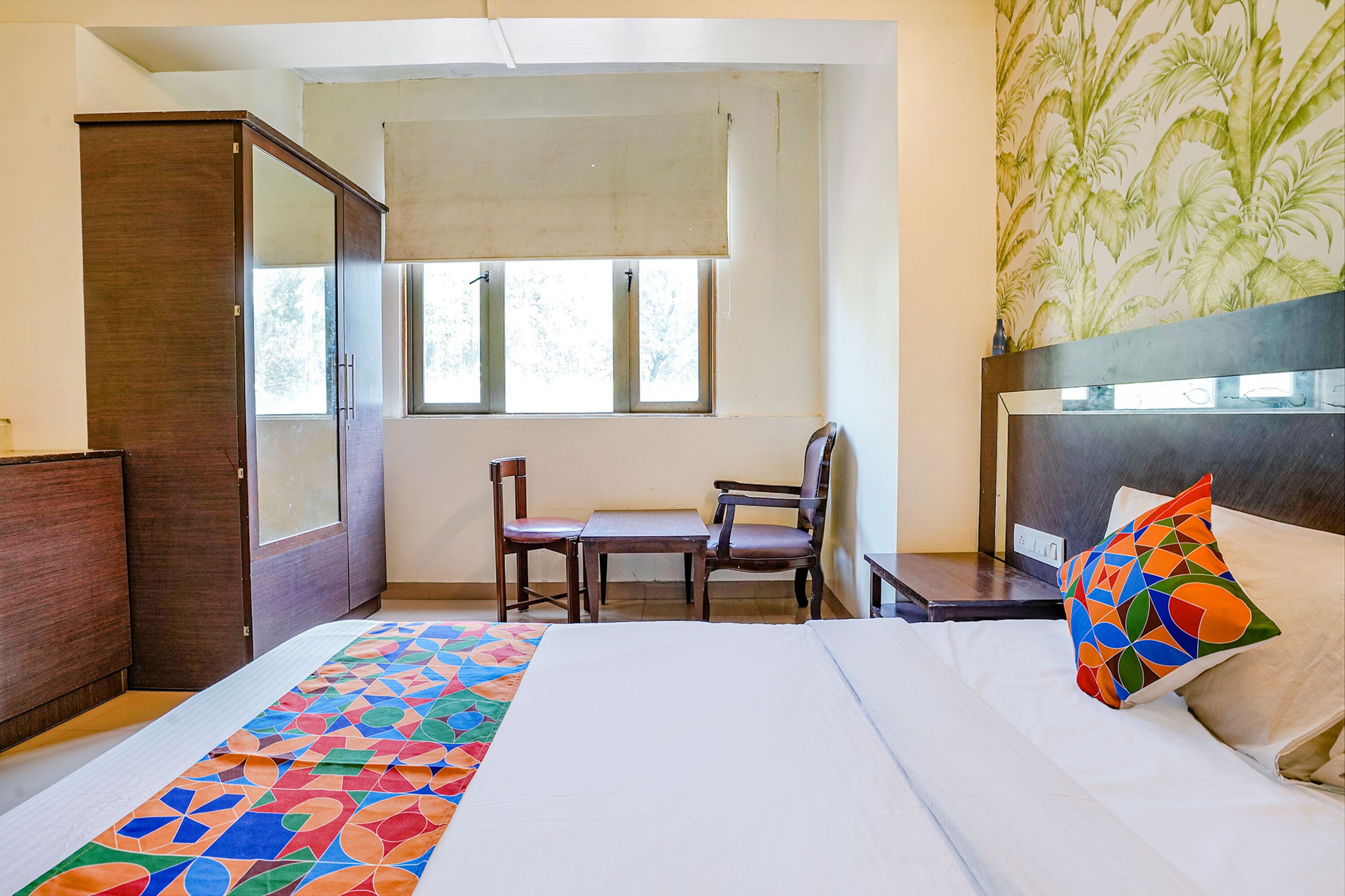 A hotel room with a bed, a desk, a chair, and a wardrobe.