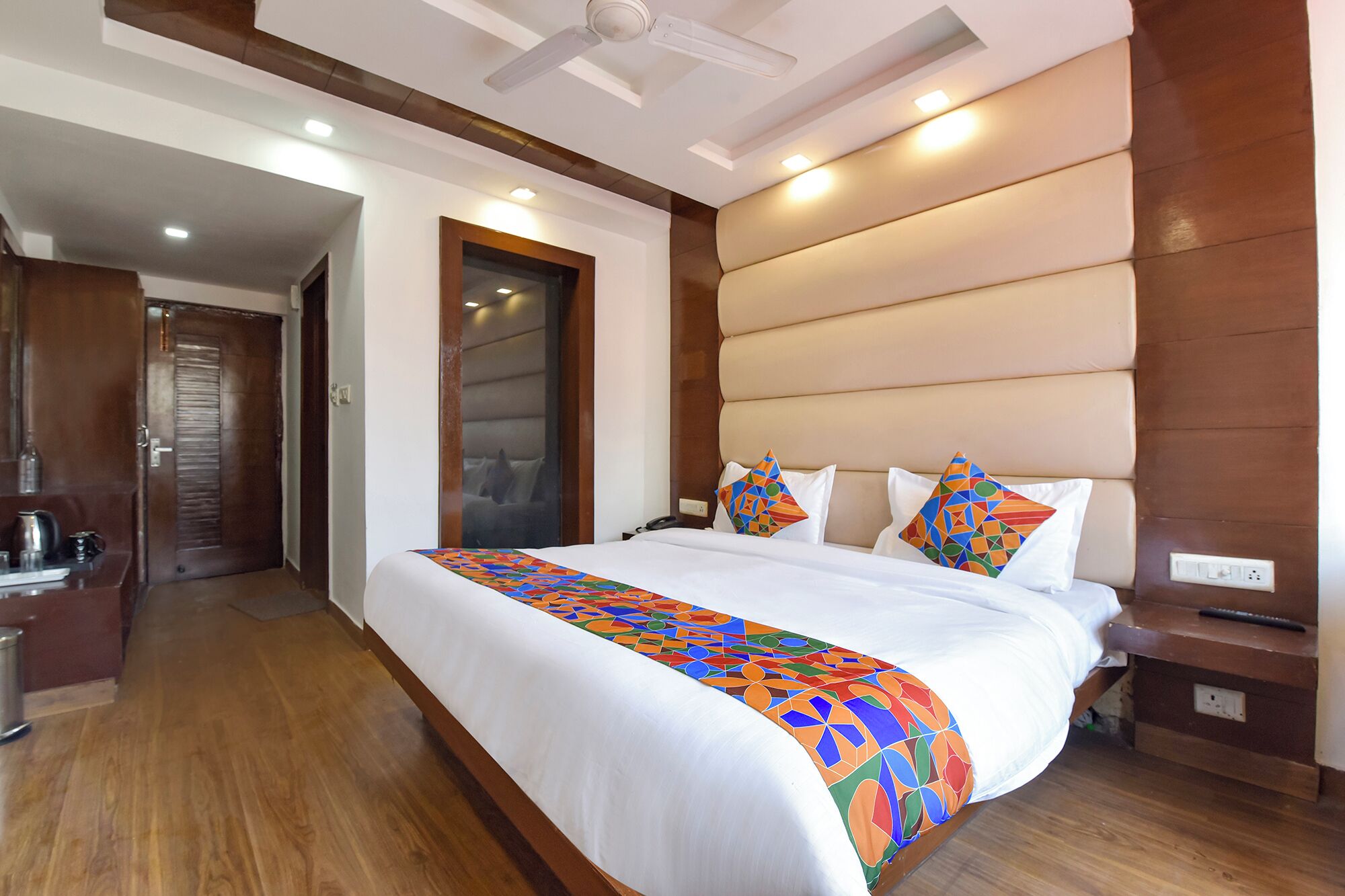 Habitación de hotel con una cama grande, un cabecero de madera, una mesita de noche y un escritorio con una silla.