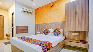 Quarto de hotel moderno com uma cama grande, um guarda-roupa de madeira e um aparelho de ar condicionado.