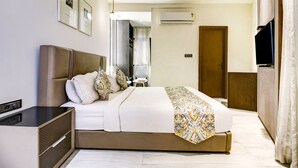 A modern hotel room with a large bed, a bedside table, an air conditioning unit, and a television.