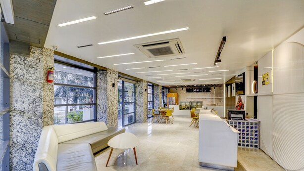 A modern hotel lobby with marble walls, a reception desk, seating area, and large windows offering views of the outdoors.