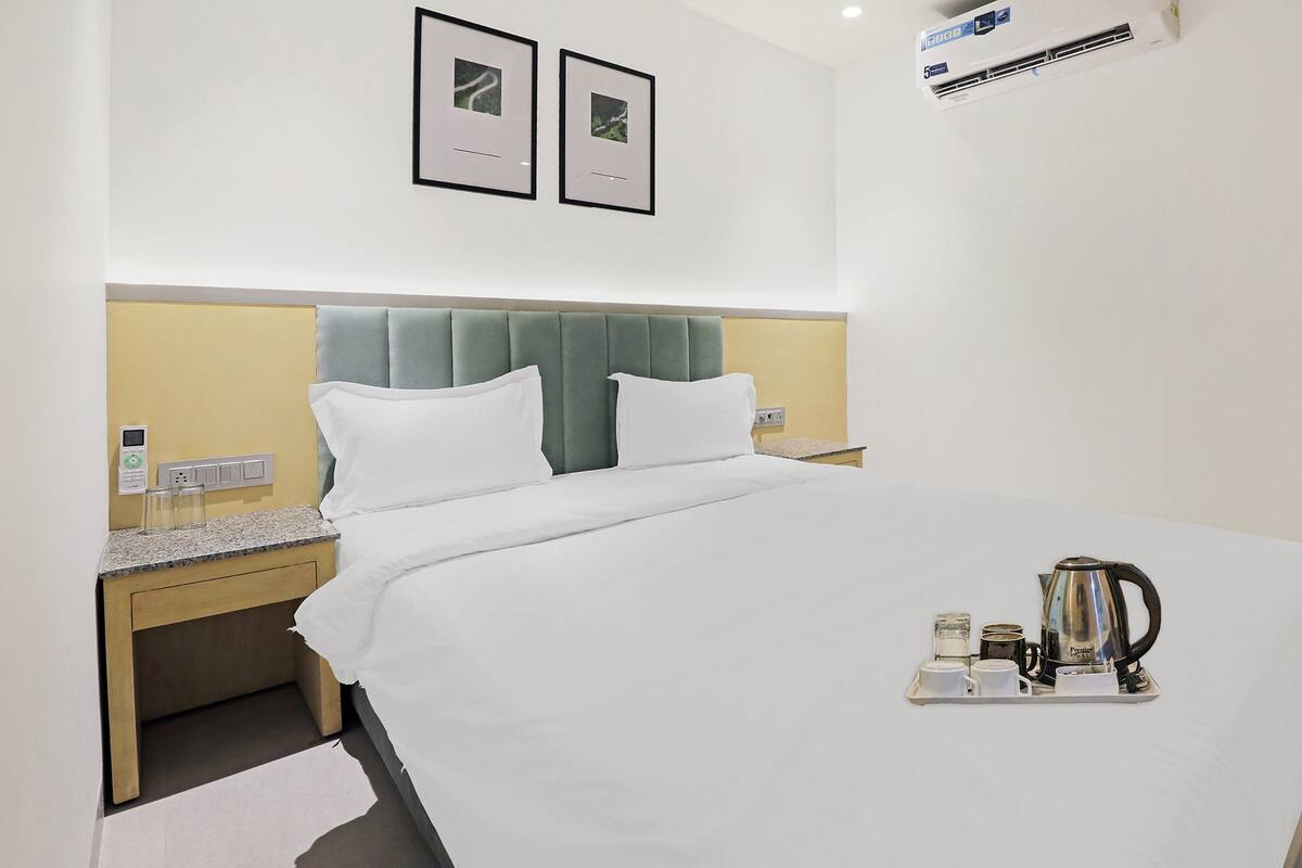 Une chambre d’hôtel avec un lit, des tables de chevet, un plateau avec une machine à café et des tableaux encadrés au mur.