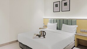 A hotel room with a neatly made bed, a bedside table with a lamp, and a tray with a kettle and cups. - FabHotel Yellow Courtyard (Bhopal)