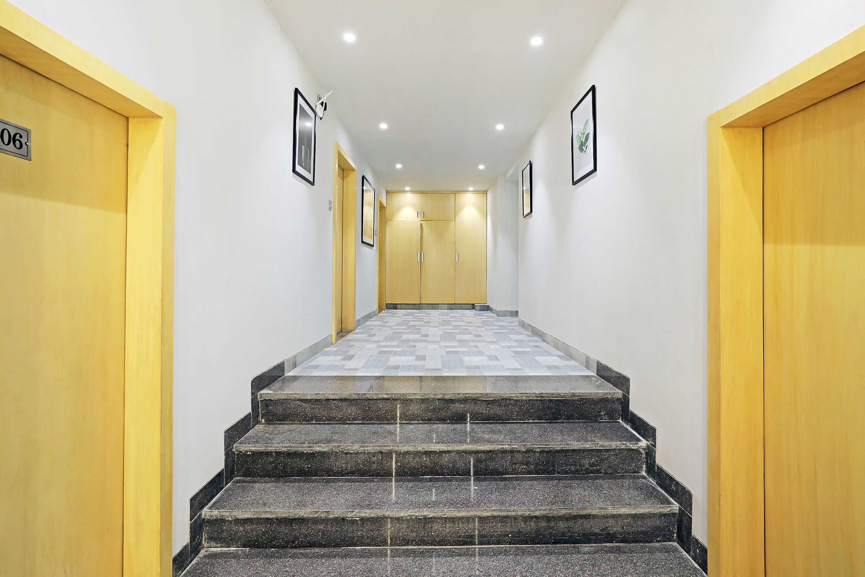 A hotel hallway with a carpeted staircase, wooden doors, and framed pictures on the walls.