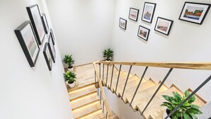 A staircase with wooden steps and a metal railing, surrounded by white walls and framed pictures. - FabHotel Yellow Courtyard (Bhopal)