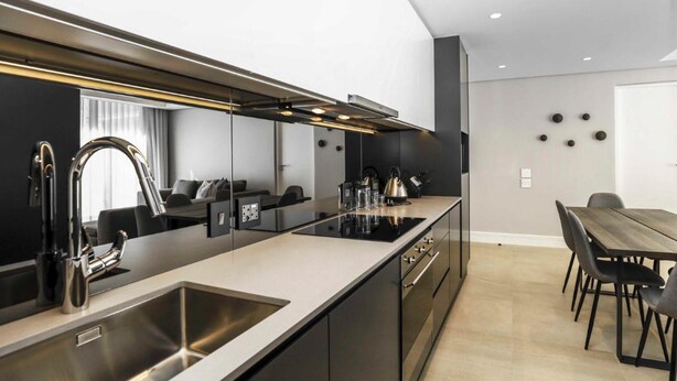 A modern kitchen with a large island, stainless steel appliances, and a dining area with a wooden table and chairs.