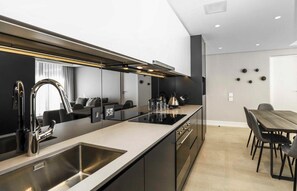 Eine moderne Küche mit einer großen Kochinsel, Edelstahlgeräten und einem Essbereich mit Holztisch und -stühlen.