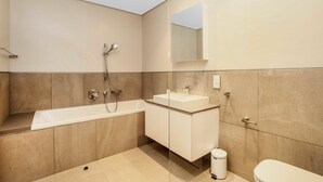 A modern bathroom with a bathtub, a sink, and a toilet.