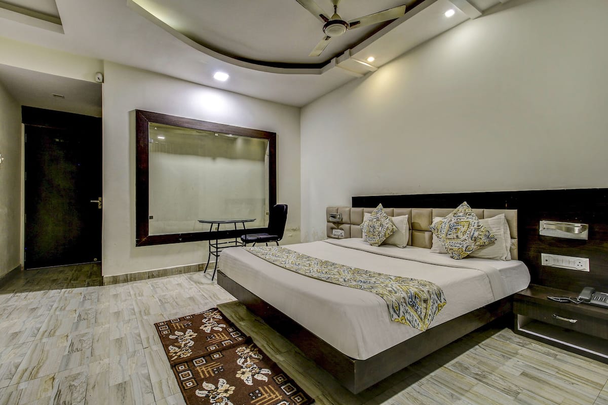 A bedroom with a bed, bedside table, and a large window.