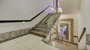 A modern staircase with granite steps and a metal railing, leading to a landing with a stone wall and a mirror. - Fabhotel Csfc (Bhopal)