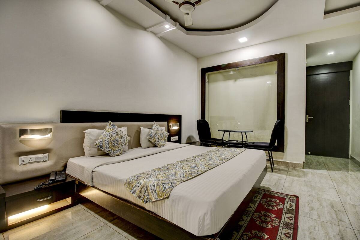 A modern hotel room with a large bed, bedside tables, a desk, and a chair.