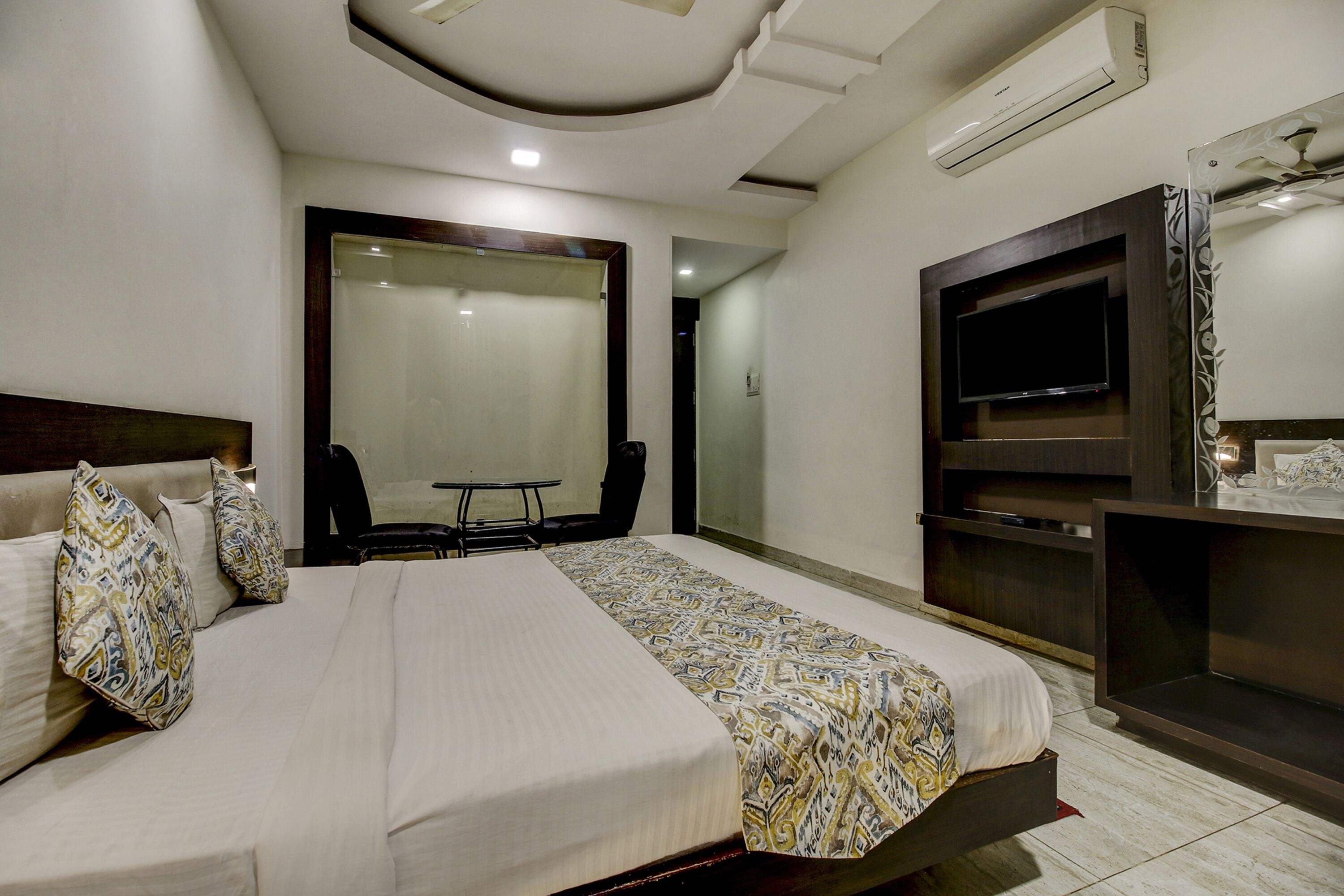 A hotel room with a large bed, a TV, a desk, and a chair.