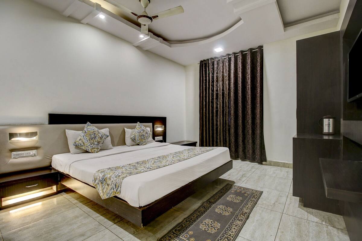 A modern bedroom with a large bed, bedside tables with lamps, a ceiling fan, and a dark wood cabinet.