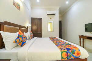 Una habitación de hotel con una cama, televisión, armario y aire acondicionado.