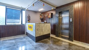 A hotel reception area with a marble counter, wooden paneling, and an elevator. - Fabhotel Gargi Inn (Pune)