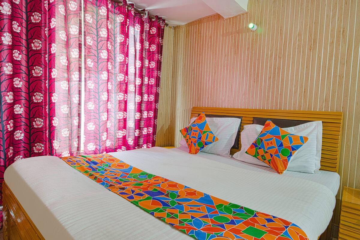 Una cama bien hecha con un corredor de cama de estampado geométrico colorido, un cabecero de madera y dos almohadas con diseños geométricos.