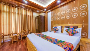 A hotel room with a large bed, wooden headboard, a desk, and a wardrobe. - FabHotel Sapphire (Dehradun)