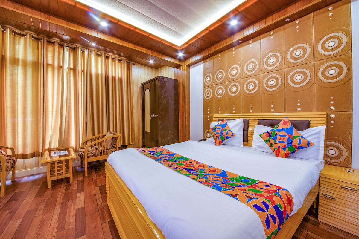 Una habitación de hotel con una cama grande, cabecero de madera, un escritorio y un armario.