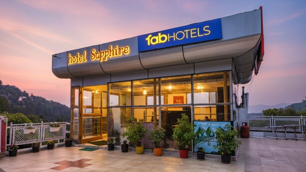 A hotel named 'Hotel Sapphire' with a modern glass facade, a signboard, and potted plants in front. - FabHotel Sapphire (Dehradun)