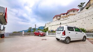 A parking area with two cars, a white car and a red car, parked on a tiled surface. - FabHotel Sapphire (Dehradun)