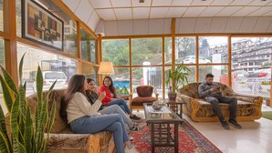 A spacious lobby with large windows, a coffee table, and seating arrangements. - FabHotel Sapphire (Dehradun)
