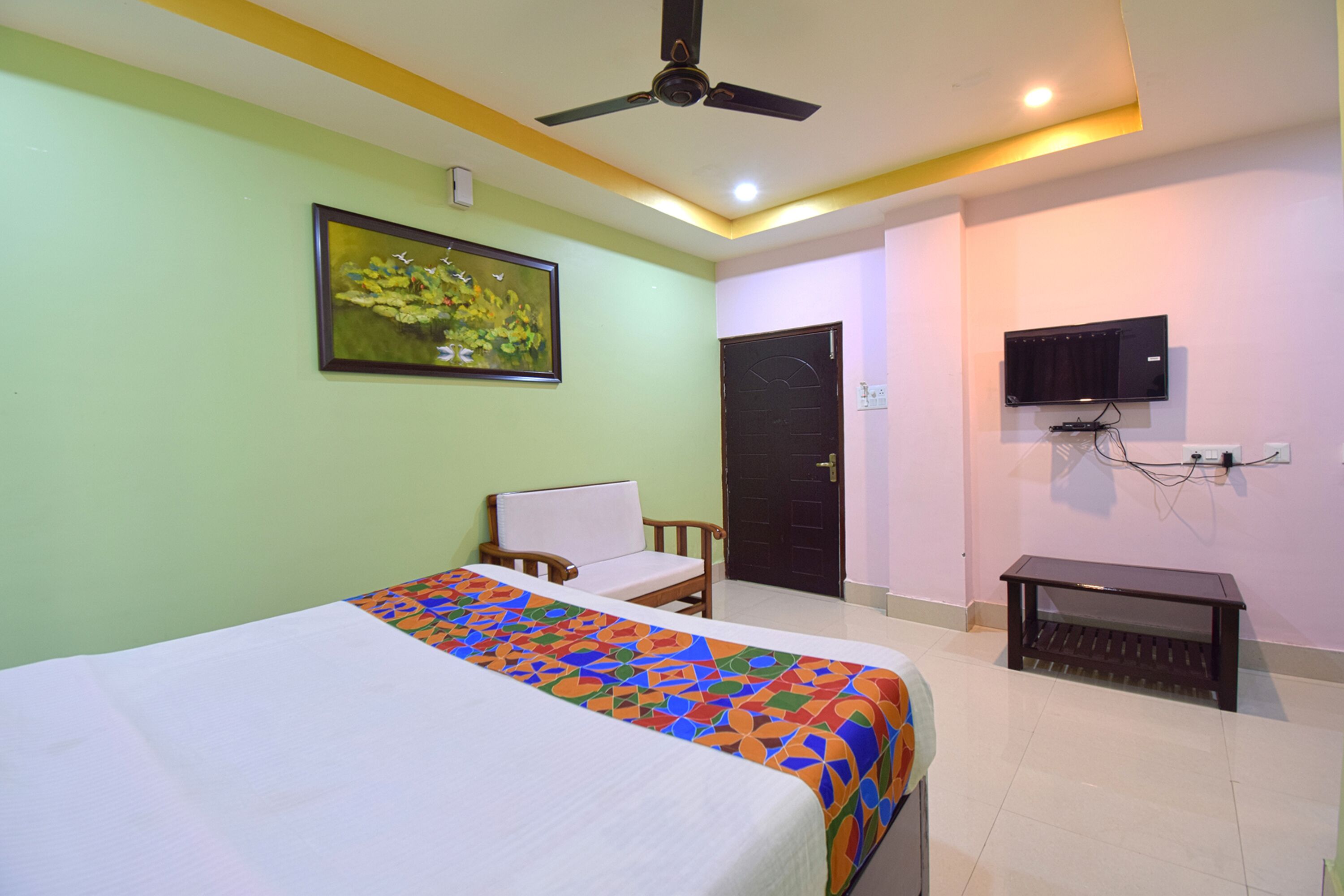 Una habitación de hotel con cama, una silla, televisor y puerta.