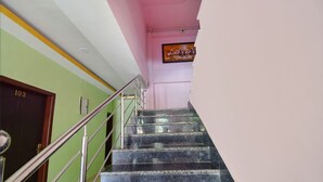 A staircase with metal railings leading to a room with a green wall and a door labeled "103". - Fabhotel Knight Airways (Guwahati)