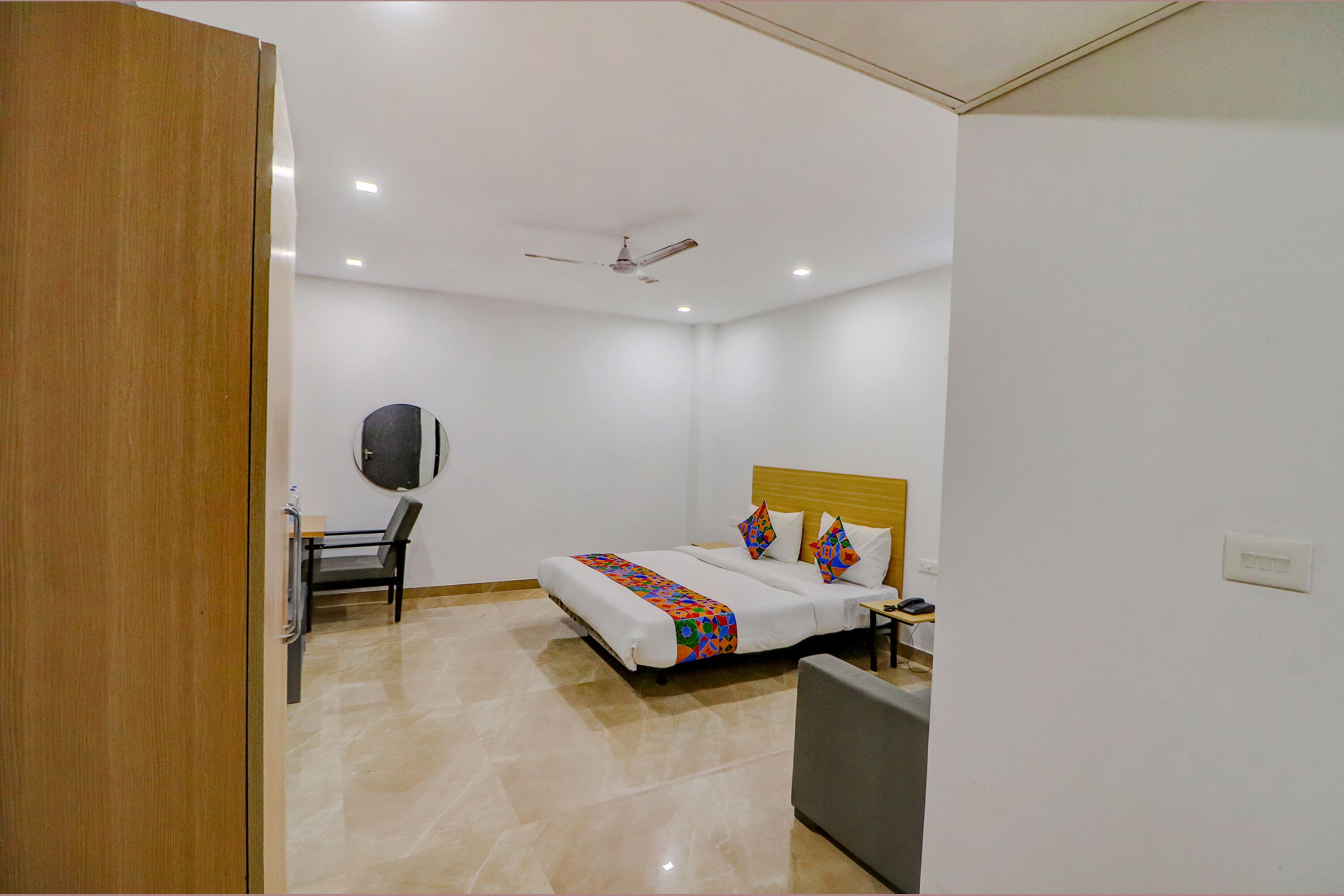 A hotel room with a bed, a desk, a chair, a television, and a ceiling fan.