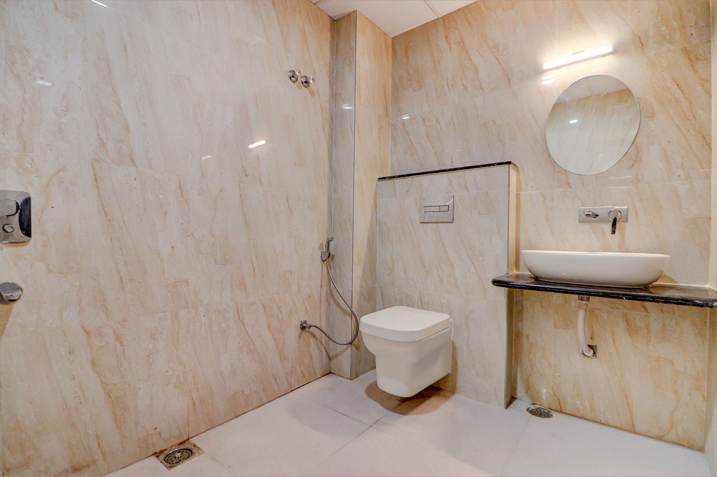 A modern bathroom with a marble wall, a toilet, a sink with a mirror, and a shower.