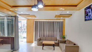 A modern lobby with a sofa, a coffee table, and a TV screen on the wall. - FabHotel The Shashi - Nr. Sarnath Temple (Varanasi)