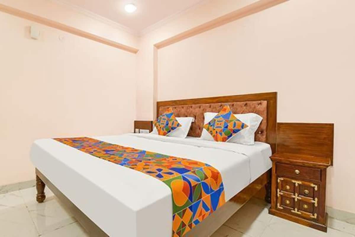 Una cama bien hecha con un colorido edredón de estampado geométrico, un cabecero de madera y una mesita de noche con cajones.