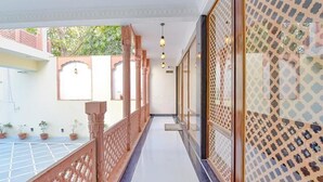 A corridor with a wooden railing, a tiled floor, and a patterned wall. - FabHotel JBS Heritage (Jaipur)