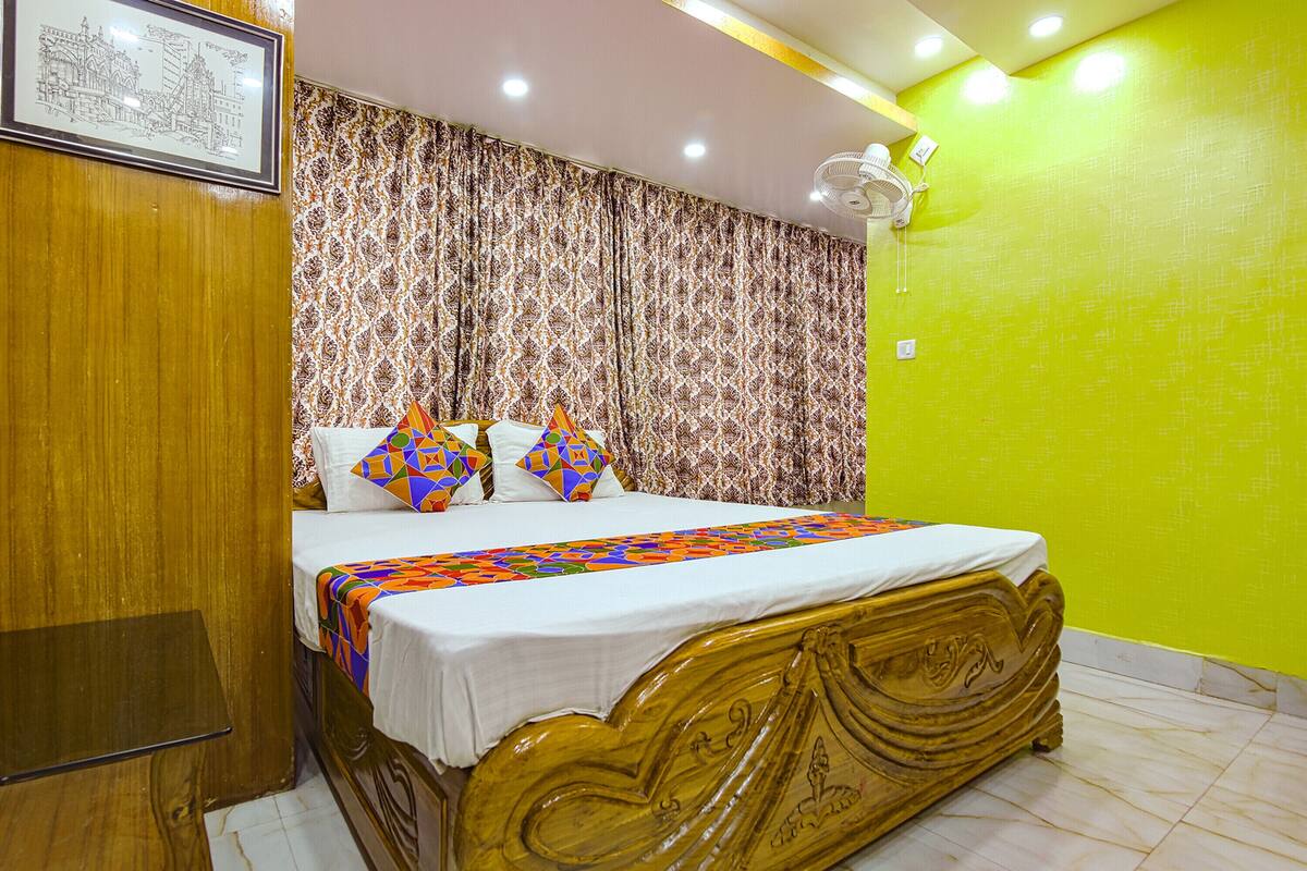 A bedroom with a wooden bed frame, patterned curtains, and a bright green wall.