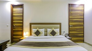 Ein Hotelzimmer mit einem großen Bett, einem Holz-Kopfteil, zwei Nachttischen mit Lampen und zwei Türen.