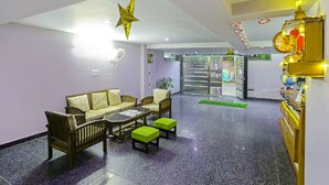 Eine Lobby mit einer Couch, Sesseln, einem Couchtisch und einer grünen Matte.