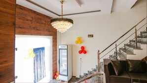 Ein Zimmer mit einem Kronleuchter, einem Kühlschrank, Luftballons, einer Treppe und einem Sofa.