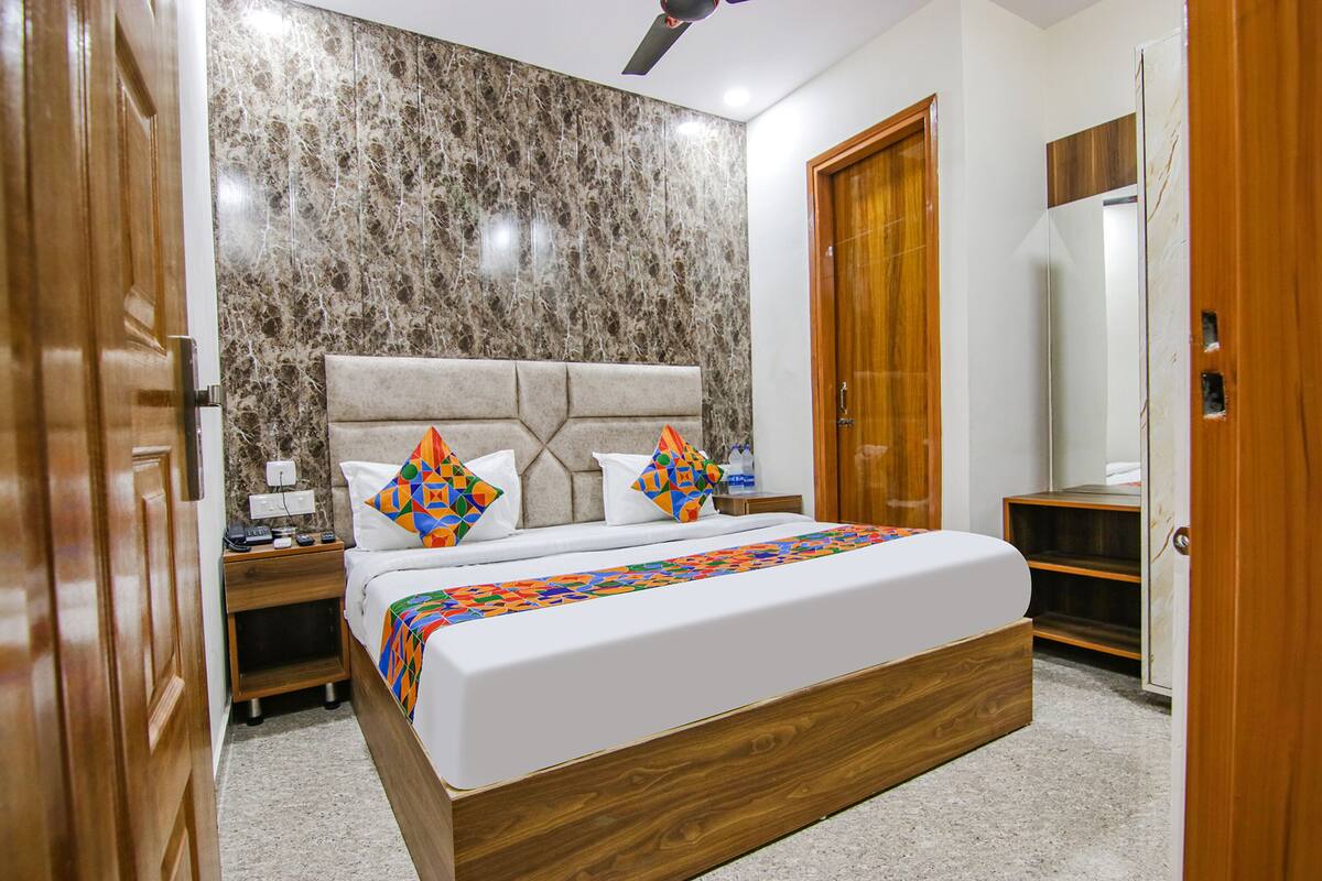 Quarto com uma cama grande, cabeceira de madeira e parede com padrão marmorizado.